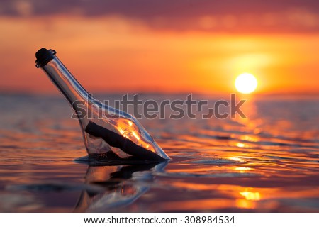 Bottle with a message in the sea at sunset