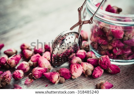 Rose buds tea, tea strainer and glass jar. Selective focus.
