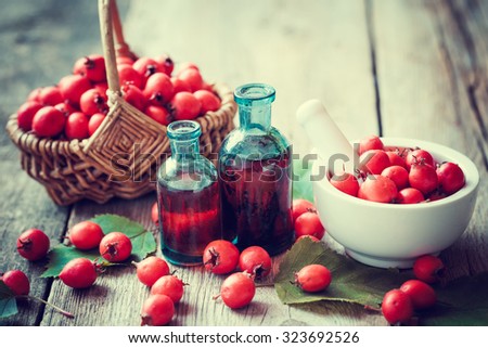 Mortar of  hawthorn berries, two tincture bottles and thorn apples in basket on rustic table. Herbal medicine. Selective focus.