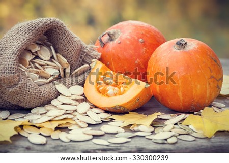 Pumpkins and canvas bag with pumpkins seeds on wooden table. Selective focus.