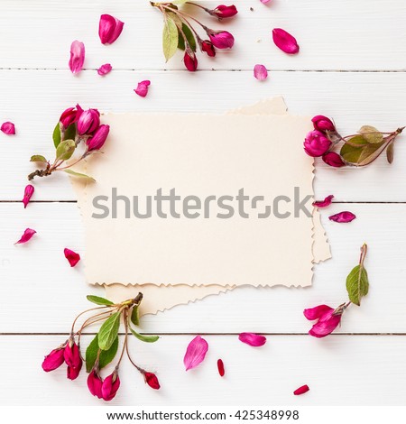 Old empty photo for the inside and frame of apple flowers on white wooden background. Flat lay, top view.