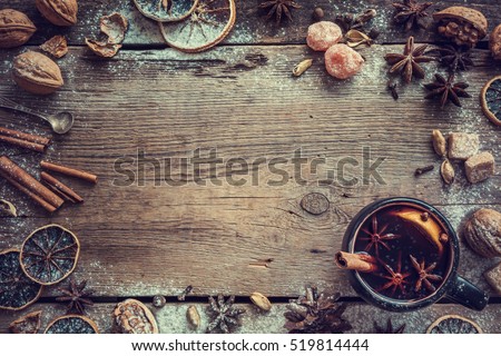 Mulled wine in rustic mug with spices and ingredients on wooden background. Top view, flat lay. Retro toned photo. Copy space for your text.