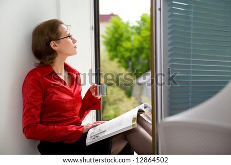 Business woman drinks coffee and reads magazine at office