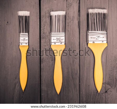 Three paint brushes lie on three boards