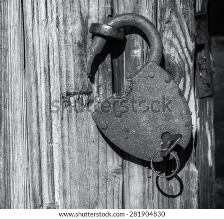Large metal lock with key inserted in it, hanging on the door handle