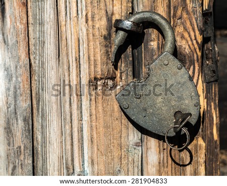 Large metal lock with key inserted in it, hanging on the door handle