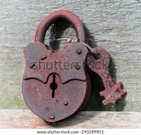 The old rusty padlock with keys lying on textured wooden boards.