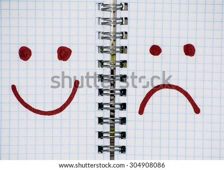 Turn paper notepad into two pages in the middle of spring. On the pages of a notebook painted a sad and cheerful emoticon.