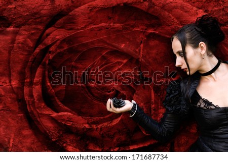 black Woman with black rose in front of a red rose blossom
