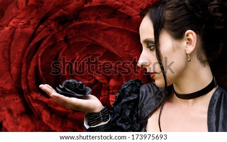 black Woman with black rose in front of a red rose blossom