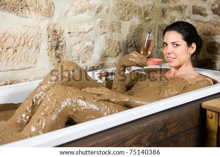 Woman in bath with clay - Health with a glass of champagne