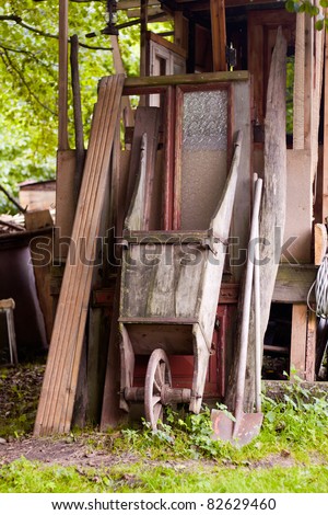 an old wheelbarrow with a shovel on an old garden shed