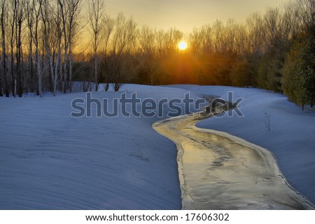 The setting sun lights up the ice on a frozen stream.