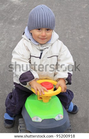 Portrait of the smiling boy driving the toy car