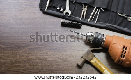 Concept of used power drill machine, hammer and some mechanic or carpentry tools kit on wooden board with room for text