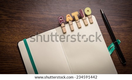 Concept of banking terms - Ratio word on clothes peg stick to notepad with pen on the side on wooden floor with room for text