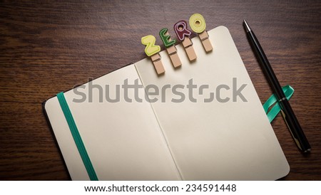 Concept of banking terms - Zero word on clothes peg stick to notepad with pen on the side on wooden floor with room for text