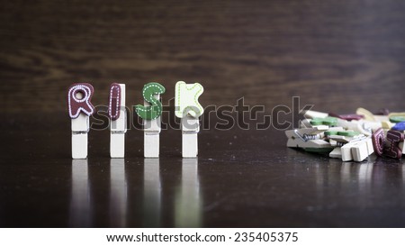 Common business terms - Slightly defocused and close-up of RISK word on clothes peg stick with lots of clothes peg at background