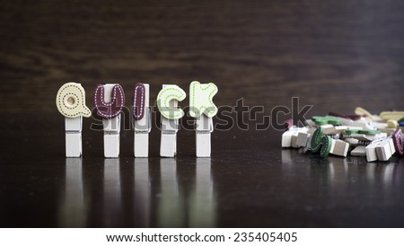 Common business terms - Slightly defocused and close-up of QUICK word on clothes peg stick with lots of clothes peg at background