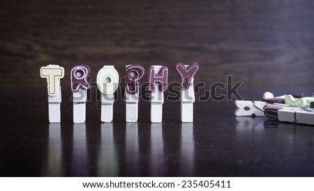 Common business terms - Slightly defocused and close-up of TROPHY word on clothes peg stick with lots of clothes peg at background