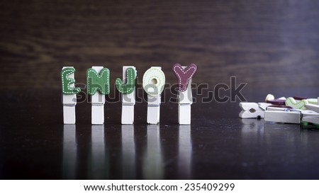 Common business terms - Slightly defocused and close-up of ENJOY word on clothes peg stick with lots of clothes peg at background