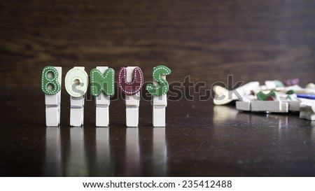 Common business terms - Slightly defocused and close-up of BONUS word on clothes peg stick with lots of clothes peg at background
