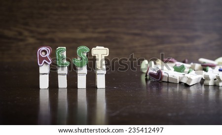 Common business terms - Slightly defocused and close-up of REST word on clothes peg stick with lots of clothes peg at background