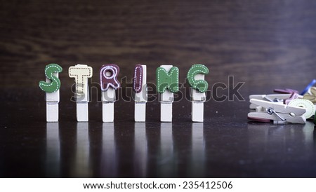 Common business terms - Slightly defocused and close-up of STRING word on clothes peg stick with lots of clothes peg at background