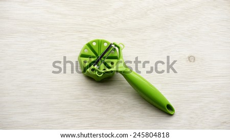 Pieces and set of stainless steel green color precision modern cutting food slicer or dicer for fruit, cheese, sausage and vegetables on wooden table surface with some room for text.