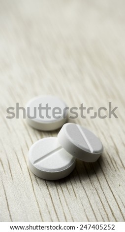 White pills on table. Pills spilling from container. Copy space. Slightly defocused and closeup shot.