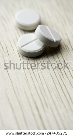White pills and bottle on table. Pills spilling from container. Copy space. Slightly defocused and closeup shot.