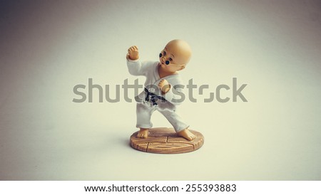 Retro color bald shaolin kungfu kid doll or martial art figurine. Concept of retro self-defence or asian martial art activities. Slightly defocused and close-up shot. Copy space.