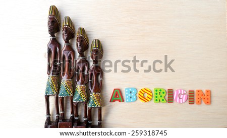 Decorative Asian or African tribal totem carved from forest wood with letter Aboriginal on clean wooden surface. Concept of aboriginal art. Slightly defocused and close-up shot. Copy space.