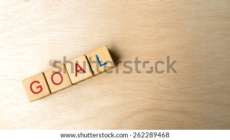 Block of alphabet letters forming the word GOAL on wooden surface. Concept of common marketing business terms. Slightly defocused and close-up shot. Copy space.