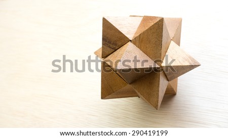 Wooden pointy cube puzzle on wooden surface. Concept of complex and smart logical thinking. Slightly defocused and close up shot. Copy space.