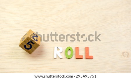 Wooden dice on a wooden table surface with alphabet ROLL. Concept of luck, chance, gamble and probability. Copy space.