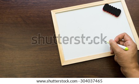 Hand writing on empty white boards on wooden surface. Concept of school or business message. Slightly de-focused and close-up shot. Copy space.