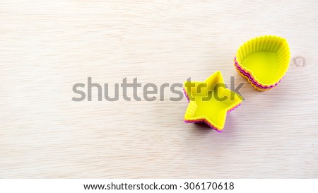 Silicone molds with starry and love shapes of different colors on a wooden surface. Concept of funky bakery or utensils for young chef. Slightly de-focused and close-up shot. Copy space.