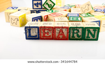 Cute and colourful wooden block forming word LEARN. Concept of learning education. Isolated on white background. Slightly de-focused and close-up shot. Copy space.