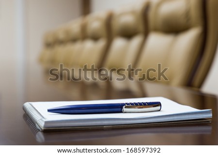Closeup of notepad for agenda kept on table in empty corporate conference room before business meeting