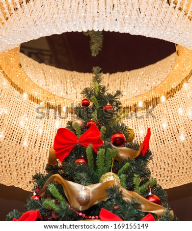 Tall christmas tree with round chandelier on a ceiling