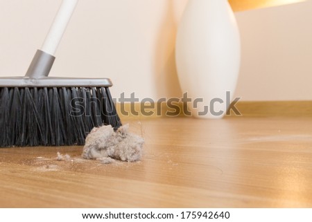 Sweeping dust with black broom on a wooden floor