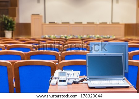 Conference hall with rows of blue seats and rostrum