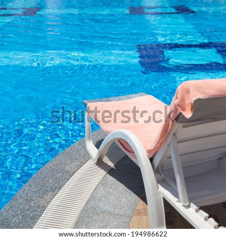 Sunbed covered with towel on edge of a pool