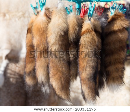 a lot of fox tails hanging in a street market