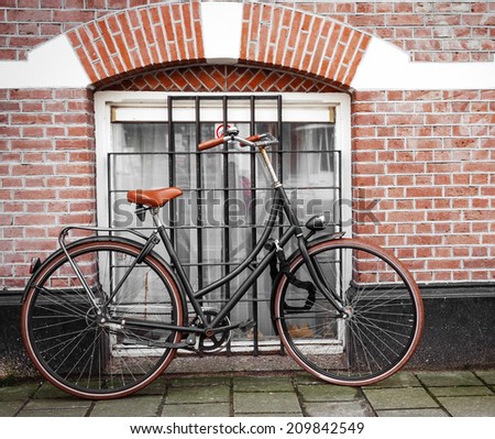 Bicycle leaning against a street level window with metal burglar bars in a red brick building with arched brickwork over the window