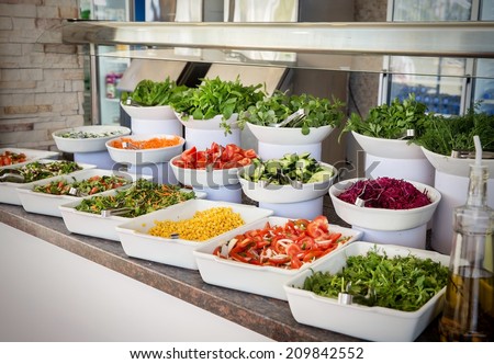 Selection of assorted healthy fresh salads displayed in individual dishes at a restaurant or catered event, healthy food