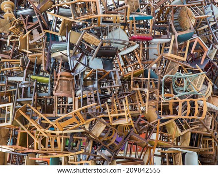 Stack of assorted metal and wooden chairs in random disarray, full frame background image