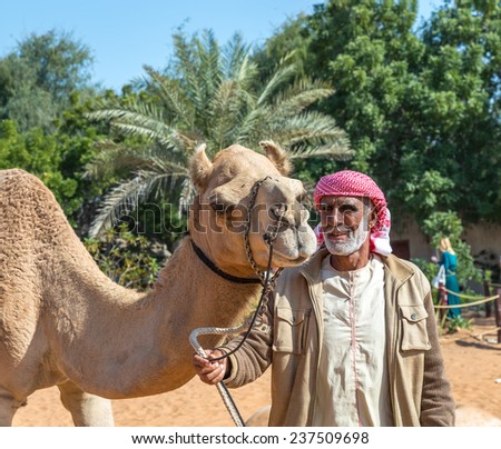 ABU DHABI, UNITED ARAB EMIRATES - JANUARY 18:  Bedouin holding camel in Heritage village museum on January 18, 2014 in Abu Dhabi, UAE.