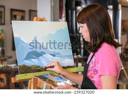 Young woman painting mountains in art studio